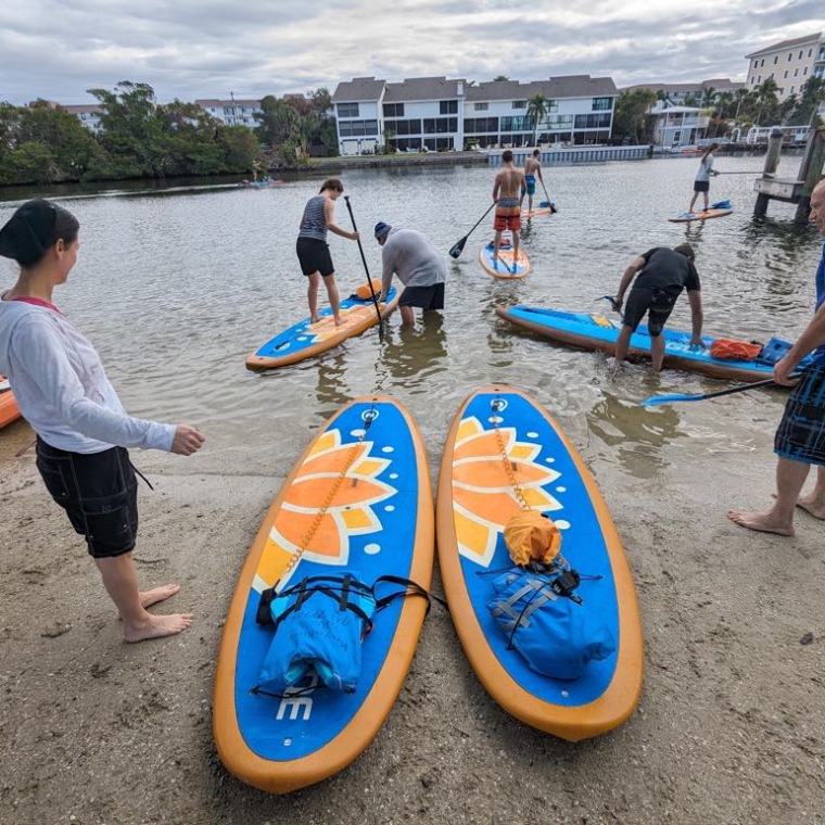 a group of people on a beach holding a surf board